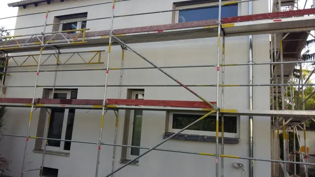 Eingerüstetes Wohnhaus mit neuen Fenstern