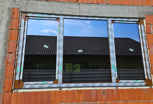 Zwei neu montierte braune Kunststofffenster in einer Ziegelwand